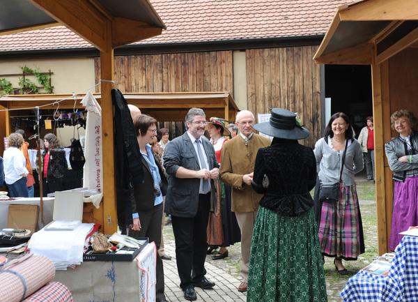 Unter den Besuchern des Trachtenmarktes befanden sich auch Landrat Dr. Günther Denzler (Landkreis Bamberg) und Landrat Michael Busch (Landkreis Coburg). Im Hintergrund sind Stände und Personen in Tracht zu sehen.