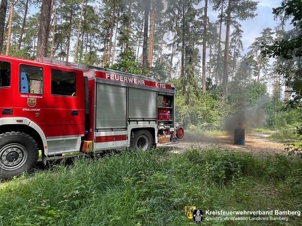 Feuerwehrfahrzeug vor einer brennenden Tonne - bung zur Waldbrandfrherkennung