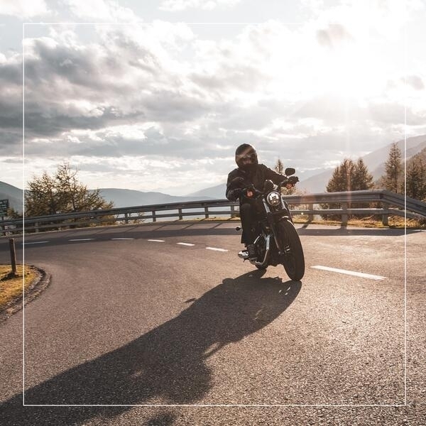 Ein Motorradfahrer fhrt eine Kurve. Im Hintergrund ein Bergpanorama.